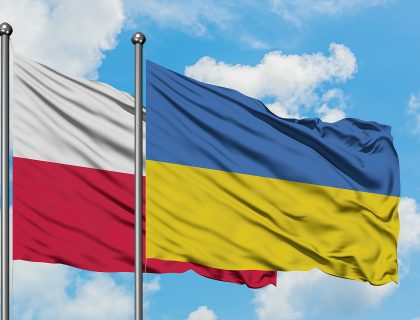 Poland and Ukraine flag waving in the wind against white cloudy