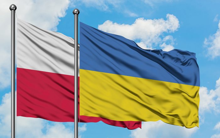 Poland and Ukraine flag waving in the wind against white cloudy